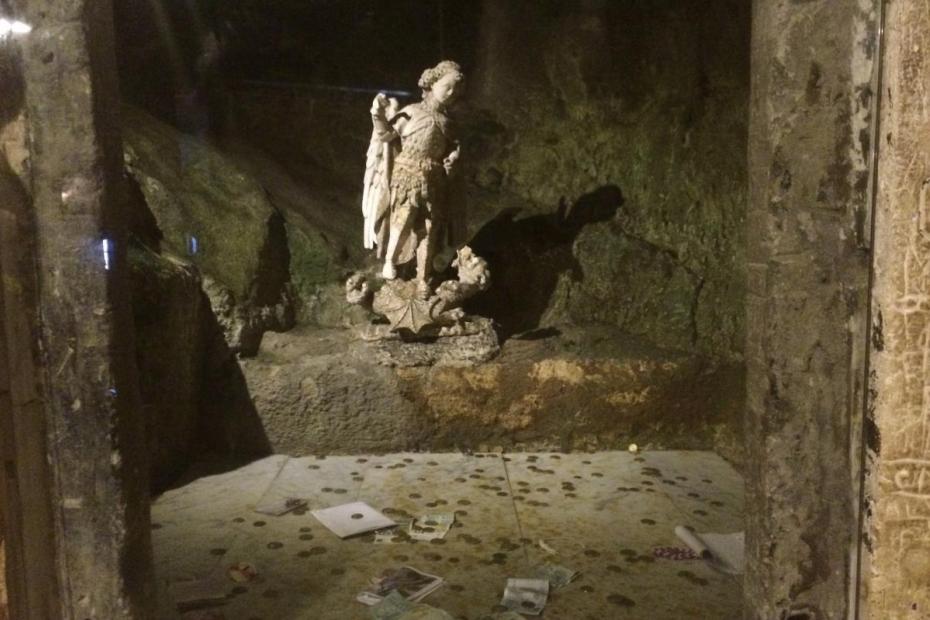 Offerings thrown behind the glass at a statue of San Michele, in a side grotto of the cave, Monte Sant'Angelo, Apuglia, Italy.