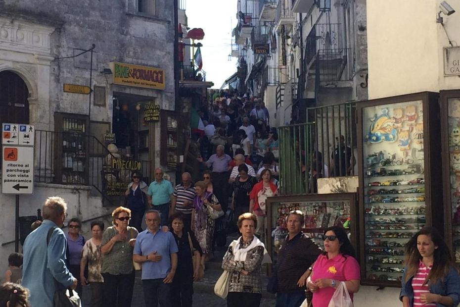 Crowds heading down the hill past the souvenir shops and toward the shrine of San Michele, Monte Sant'Angelo, Apuglia, Italy.