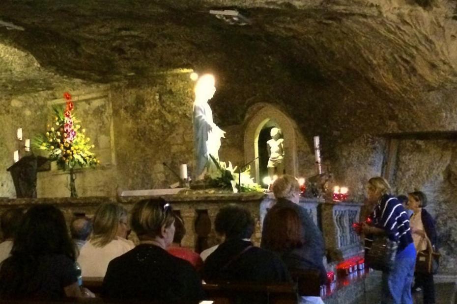 Devotees leaving candles before the altar in the cave shrine of San Michele. A statue of the Immaculate Conception has been placed at the front of the altar, while San Michele can be seen in the rear.