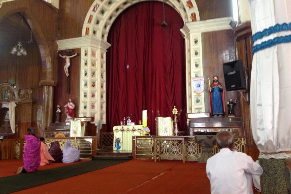Worshipers arrive early to pray at St. Mary's Forane Church, a Syro-Malabar Church, Kuravilangad. The red drape covering the sanctuary is opened during liturgy.